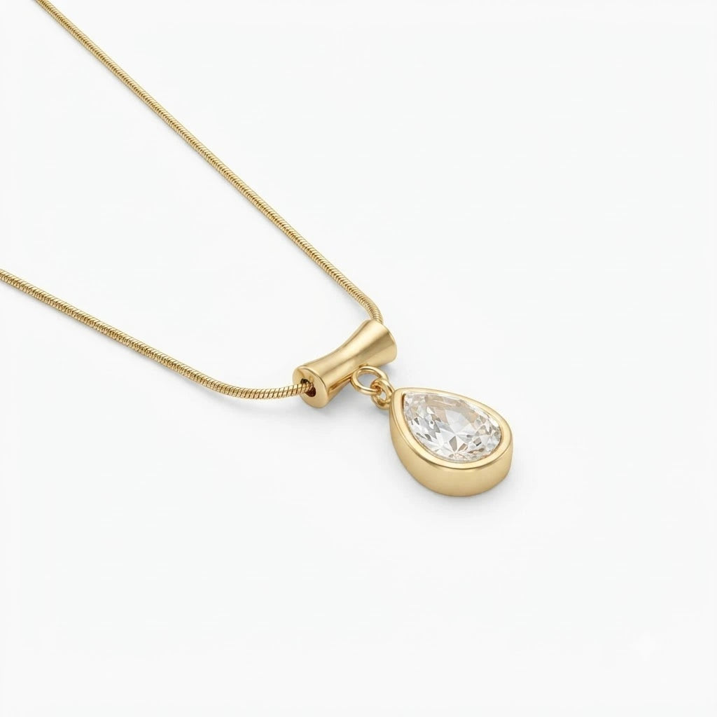 A gold pendant necklace featuring a teardrop-shaped clear gemstone in a gold bezel setting, suspended from a delicate gold snake chain against a clean white background.